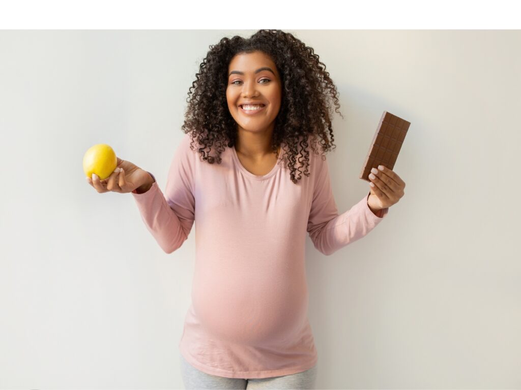 Pregnancy Cravings. Black pregnant woman holding apple and bar of chocolate de KOSTIANTYN POSTUMITENKO de Prostock-studio on Canva Pro
Premiers signes de grossesse des mamans noires